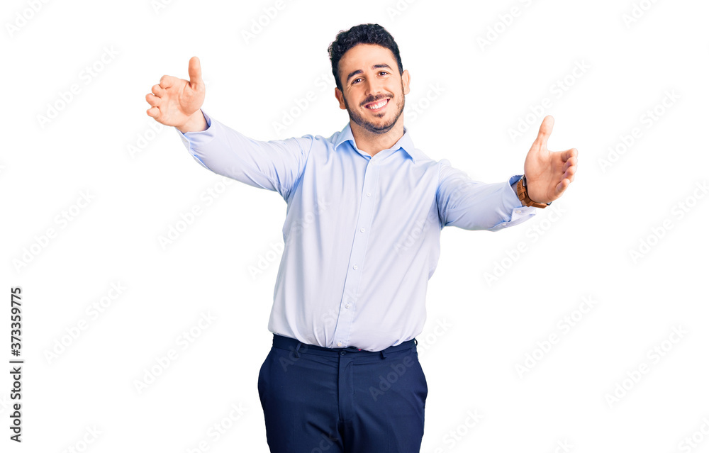 Young hispanic man wearing business clothes looking at the camera smiling with open arms for hug. cheerful expression embracing happiness. Young hispanic man wearing business clothes looking at the camera smiling with open arms for hug. cheerful expression embracing happiness.