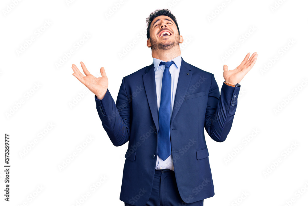 Young hispanic man wearing business clothes celebrating mad and crazy for success with arms raised and closed eyes screaming excited. winner concept Young hispanic man wearing business clothes celebrating mad and crazy for success with arms raised and closed eyes screaming excited. winner concept