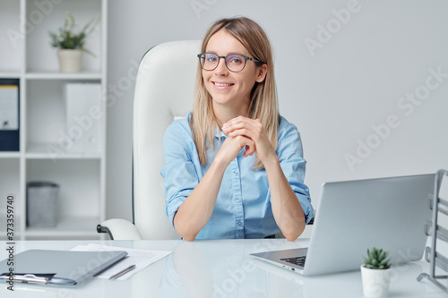Contemporary young female white collar worker sitting in armchair by desk © pressmaster