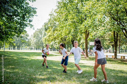 School children in white t shirts are playing with ball outside