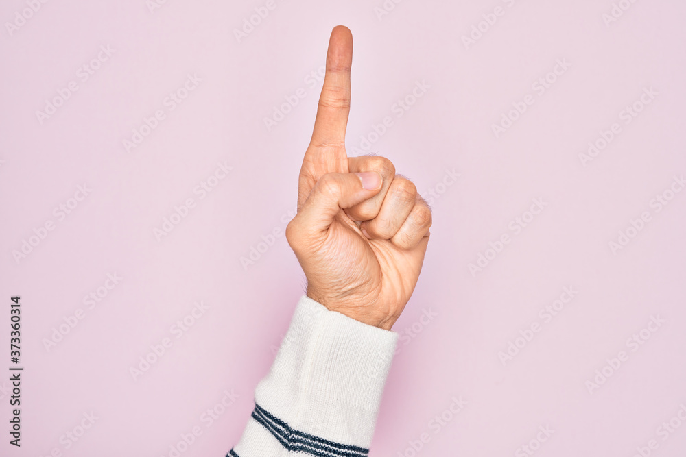 Hand of caucasian young man showing fingers over isolated pink background counting number one using index finger, showing idea and understanding
