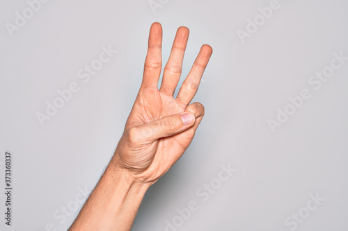 Hand of caucasian young man showing fingers over isolated white background counting number 3 showing three fingers