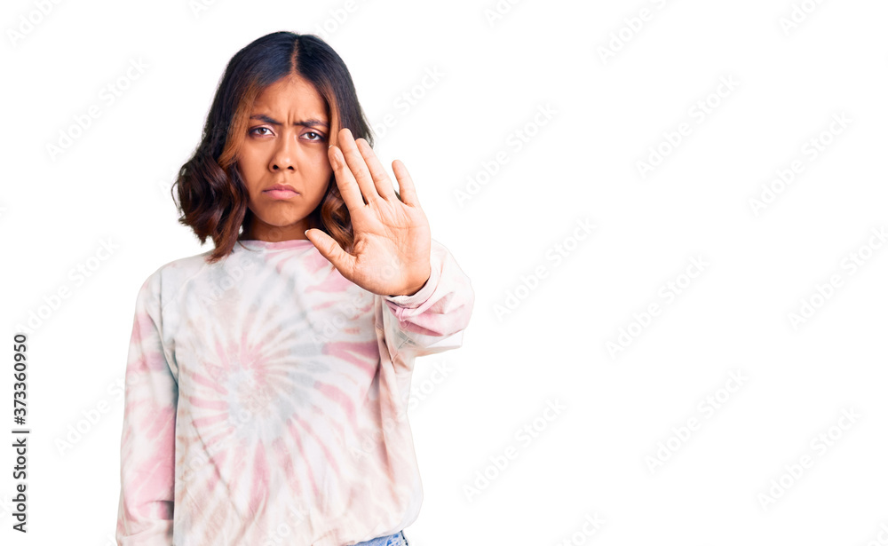 Young beautiful mixed race woman wearing casual tie dye sweatshirt doing stop sing with palm of the hand. warning expression with negative and serious gesture on the face. Young beautiful mixed race woman wearing casual tie dye sweatshirt doing stop sing with palm of the hand. warning expression with negative and serious gesture on the face.