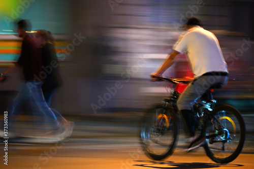 Fotografie A man rides a bicycle on a night street