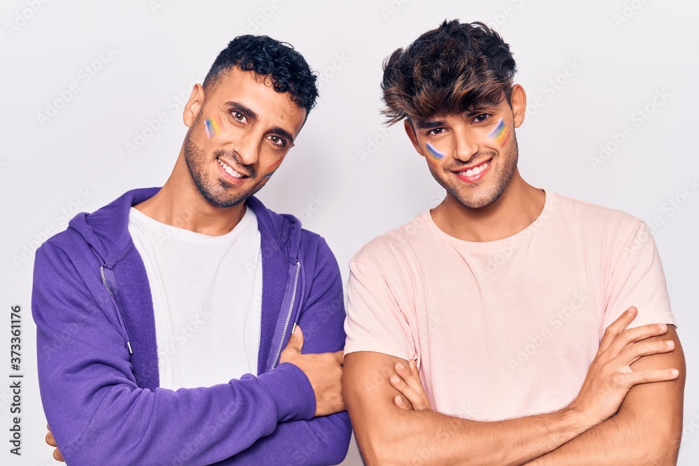 Young gay couple drawing rainbow lgtbq flag on face happy face smiling with crossed arms looking at the camera. positive person. Young gay couple drawing rainbow lgtbq flag on face happy face smiling with crossed arms looking at the camera. positive person.