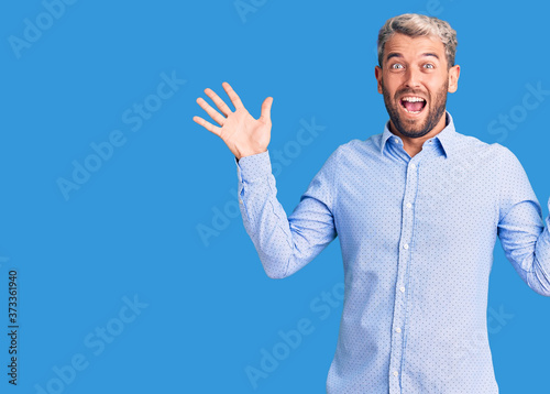 Young handsome blond man wearing elegant shirt celebrating crazy and amazed for success with arms raised and open eyes screaming excited. winner concept © Krakenimages.com