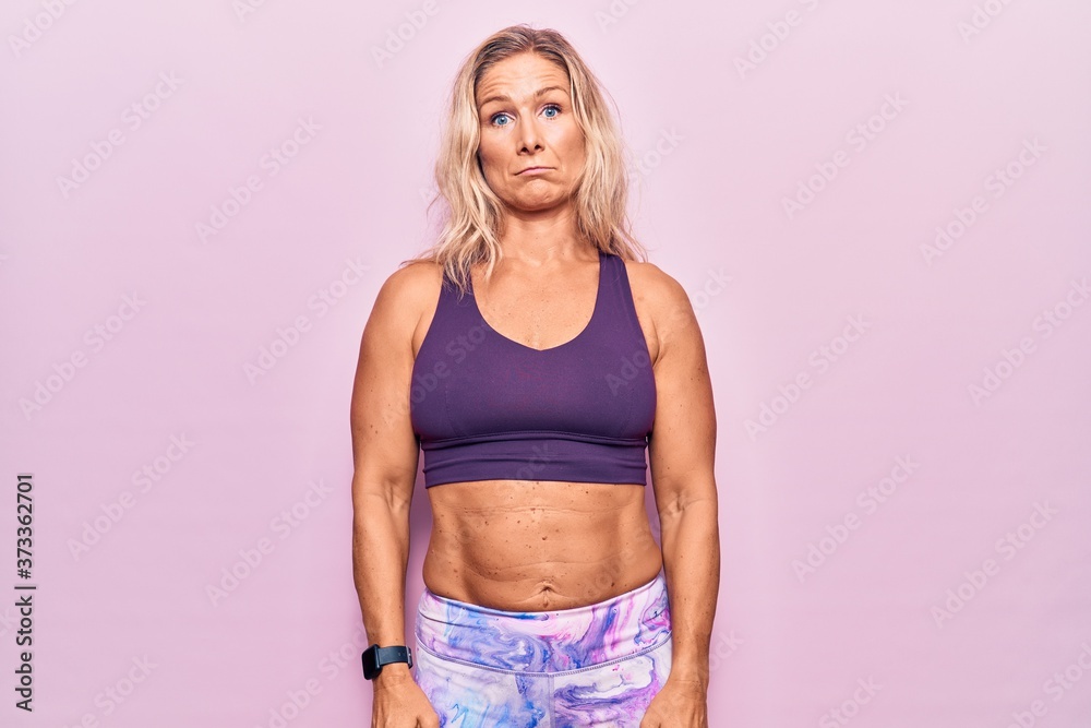 Middle age caucasian blonde woman wearing sportswear over pink background depressed and worry for distress, crying angry and afraid. sad expression. Middle age caucasian blonde woman wearing sportswear over pink background depressed and worry for distress, crying angry and afraid. sad expression.