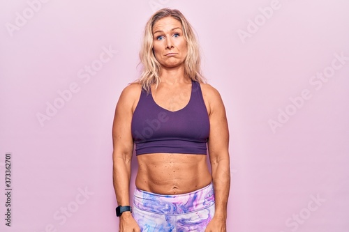 Middle age caucasian blonde woman wearing sportswear over pink background depressed and worry for distress, crying angry and afraid. sad expression.