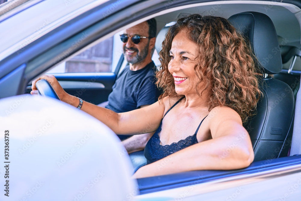 Middle age beautiful couple on vacation wearing sunglasses smiling happy driving car.