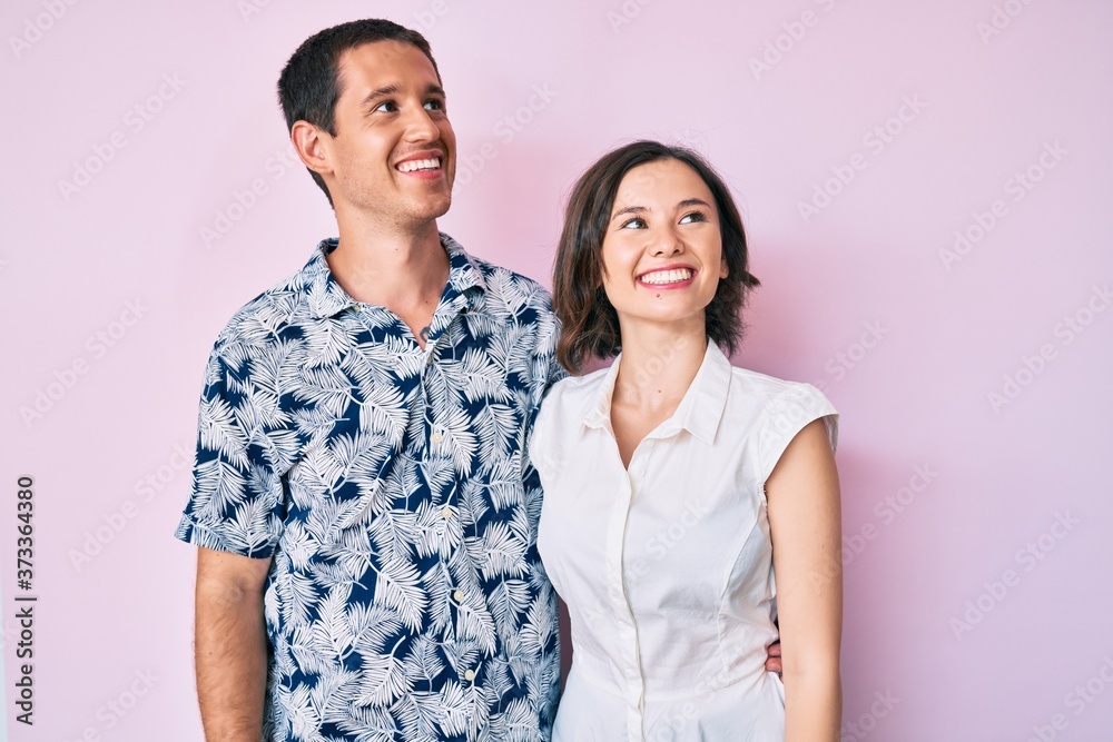 Beautiful couple wearing casual clothes looking away to side with smile on face, natural expression. laughing confident. Beautiful couple wearing casual clothes looking away to side with smile on face, natural expression. laughing confident.