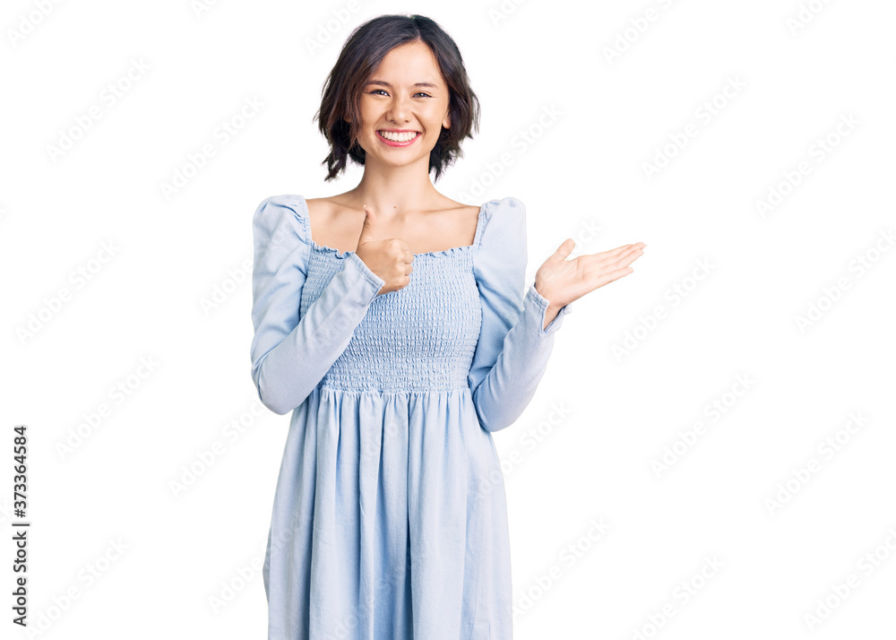 Young beautiful girl wearing casual clothes showing palm hand and doing ok gesture with thumbs up, smiling happy and cheerful Young beautiful girl wearing casual clothes showing palm hand and doing ok gesture with thumbs up, smiling happy and cheerful