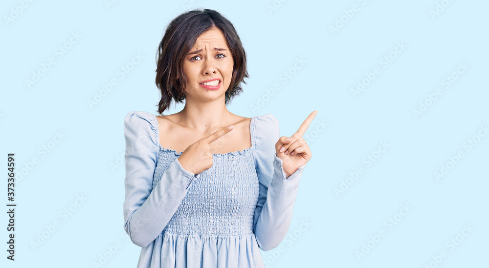 Young beautiful girl wearing casual clothes pointing aside worried and nervous with both hands, concerned and surprised expression Young beautiful girl wearing casual clothes pointing aside worried and nervous with both hands, concerned and surprised expression