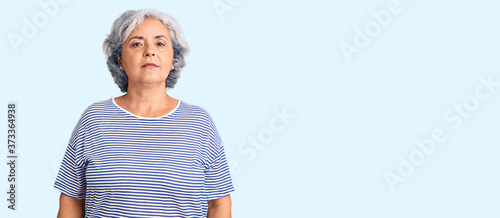 Senior woman with gray hair wearing casual striped clothes relaxed with serious expression on face. simple and natural looking at the camera. photo