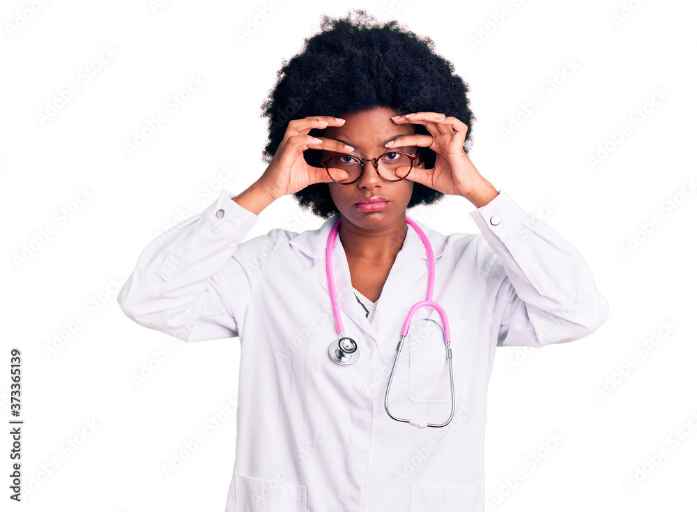 Young african american woman wearing doctor coat and stethoscope trying to open eyes with fingers, sleepy and tired for morning fatigue Young african american woman wearing doctor coat and stethoscope trying to open eyes with fingers, sleepy and tired for morning fatigue