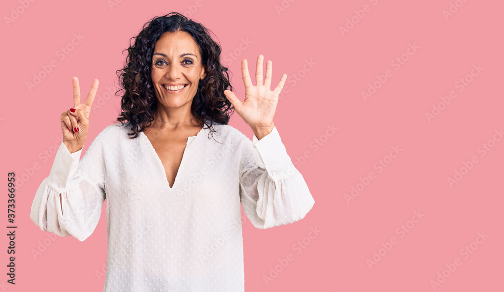 Middle age beautiful woman wearing casual sweater showing and pointing up with fingers number seven while smiling confident and happy. Middle age beautiful woman wearing casual sweater showing and pointing up with fingers number seven while smiling confident and happy.