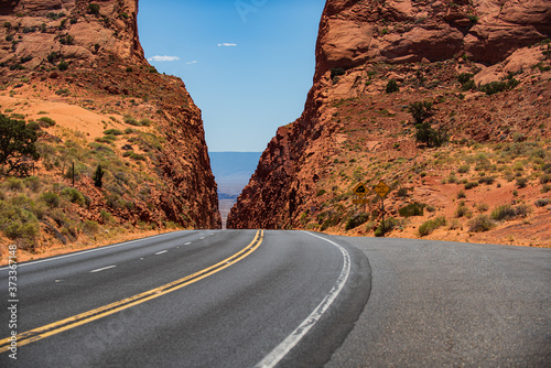 A long straight road leading towards a rocky mountain.