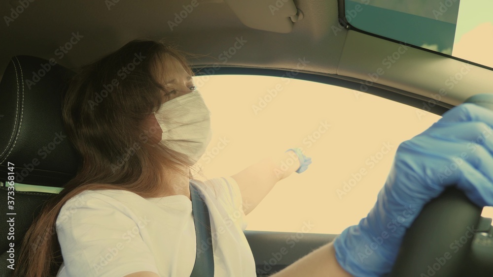Young woman driving car wearing medical mask to prevent spreading COVID-19. Driving female with face mask and gloves in car to protect from the virus flu.