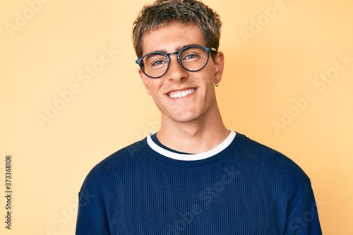 Young handsome man wearing casual clothes and glasses with a happy and cool smile on face. lucky person. © Krakenimages.com