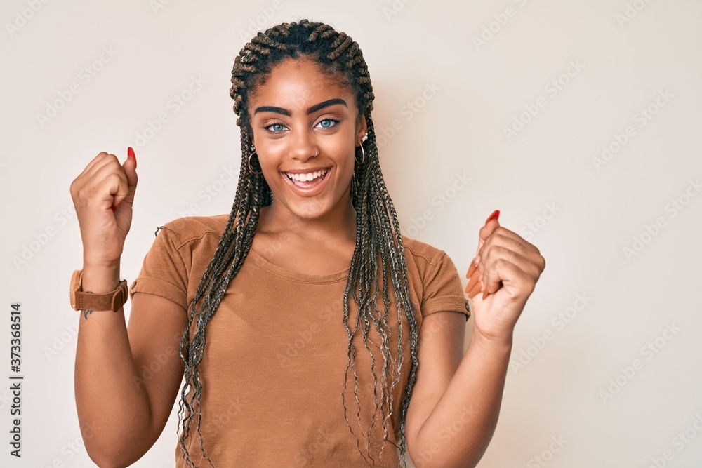 Young african american woman with braids wearing casual clothes screaming proud, celebrating victory and success very excited with raised arms
