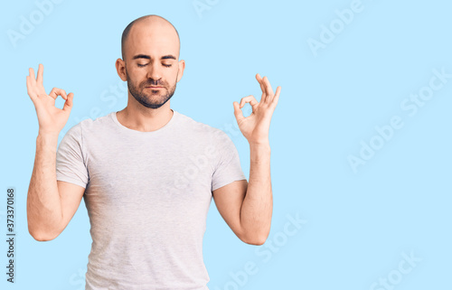 Young handsome man wearing casual t shirt relax and smiling with eyes closed doing meditation gesture with fingers. yoga concept.