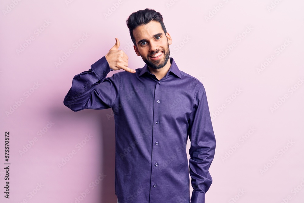 Young handsome man with beard wearing casual shirt smiling doing phone gesture with hand and fingers like talking on the telephone. communicating concepts. Young handsome man with beard wearing casual shirt smiling doing phone gesture with hand and fingers like talking on the telephone. communicating concepts.