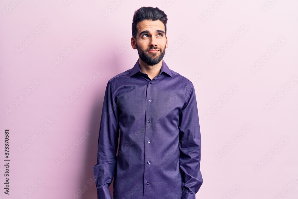 Obraz premium Young handsome man with beard wearing casual shirt smiling looking to the side and staring away thinking.