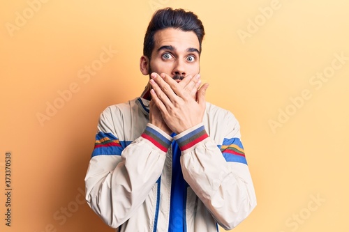 Young handsome man with beard wearing casual jacket shocked covering mouth with hands for mistake. secret concept.