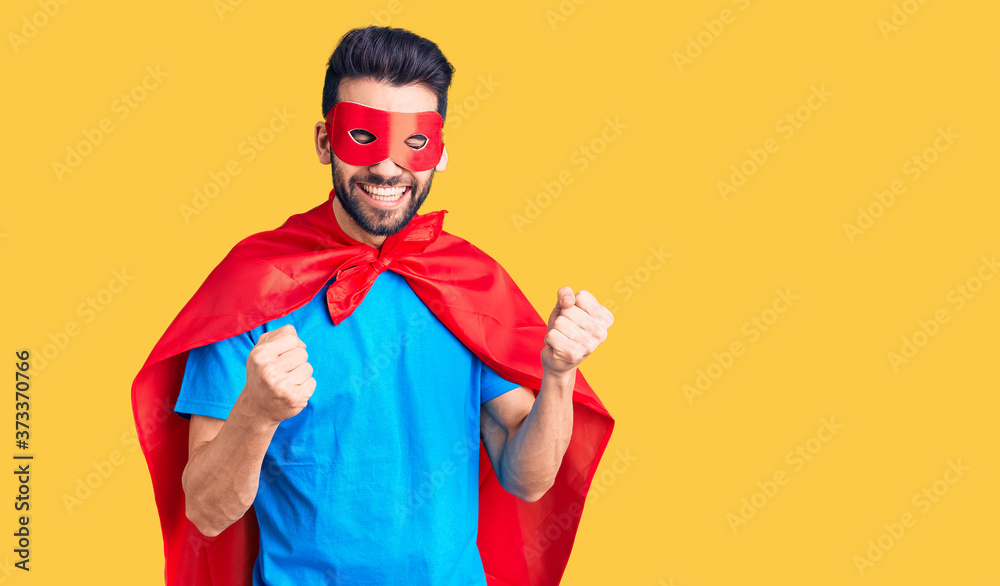 Young handsome man with beard wearing super hero costume excited for success with arms raised and eyes closed celebrating victory smiling. winner concept. Young handsome man with beard wearing super hero costume excited for success with arms raised and eyes closed celebrating victory smiling. winner concept.