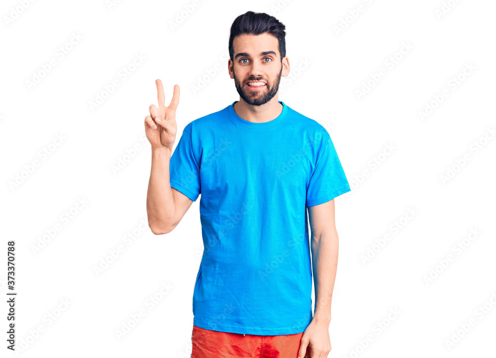 Young handsome man with beard wearing casual t-shirt smiling with happy face winking at the camera doing victory sign. number two. Young handsome man with beard wearing casual t-shirt smiling with happy face winking at the camera doing victory sign. number two.