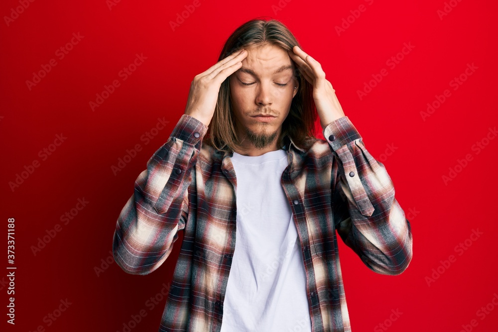 Handsome caucasian man with long hair wearing casual clothes suffering from headache desperate and stressed because pain and migraine. hands on head. Handsome caucasian man with long hair wearing casual clothes suffering from headache desperate and stressed because pain and migraine. hands on head.