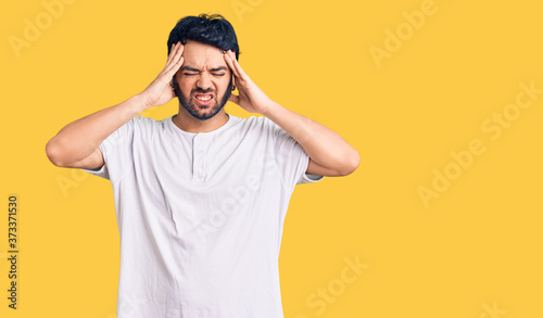 Obraz na plátně Young hispanic man wearing casual clothes suffering from headache desperate and stressed because pain and migraine