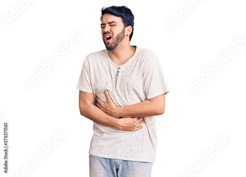 Young hispanic man wearing casual clothes with hand on stomach because nausea, painful disease feeling unwell. ache concept. © Krakenimages.com