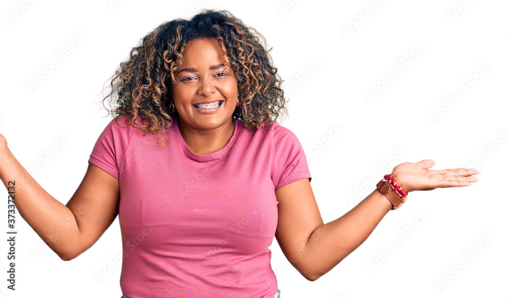 Young african american plus size woman wearing casual clothes smiling showing both hands open palms, presenting and advertising comparison and balance Young african american plus size woman wearing casual clothes smiling showing both hands open palms, presenting and advertising comparison and balance