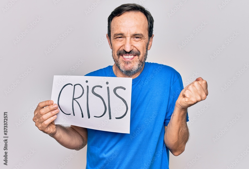 Middle age handsome man holding paper with crisis message over isolated white background screaming proud, celebrating victory and success very excited with raised arm Middle age handsome man holding paper with crisis message over isolated white background screaming proud, celebrating victory and success very excited with raised arm