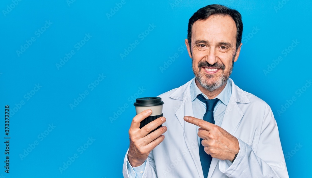 Middle age handsome doctor man wearing coat drinking cup of takeaway coffee smiling happy pointing with hand and finger Middle age handsome doctor man wearing coat drinking cup of takeaway coffee smiling happy pointing with hand and finger