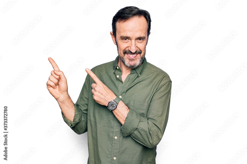 Middle age handsome man wearing casual green shirt over isolated white background smiling and looking at the camera pointing with two hands and fingers to the side. Middle age handsome man wearing casual green shirt over isolated white background smiling and looking at the camera pointing with two hands and fingers to the side.