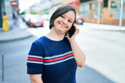 Beautiful brunette woman with down syndrome at the town on a sunny day talking on smartphone © Krakenimages.com