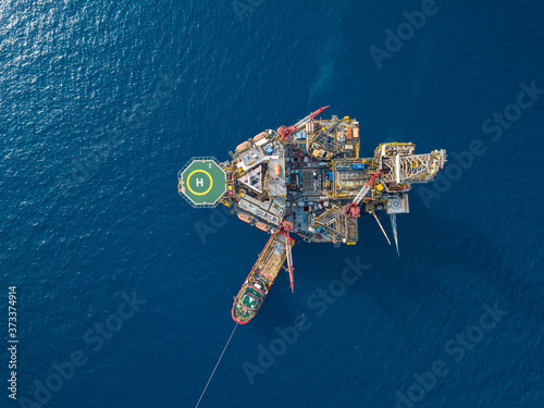 Aerial view from a drone of an offshore jack up rig at the offshore location with a supply boat