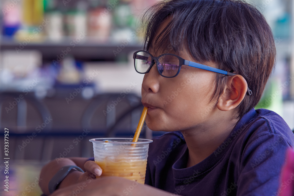 Malay asian child drinking at a hawker local style restaurant.