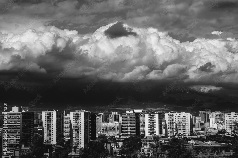 Beautiful and scenic sunlight and cloudy sky over Santiago skyline, Santa Lucía hill and the snowed The Andes Mountains, Chile (in black and white)