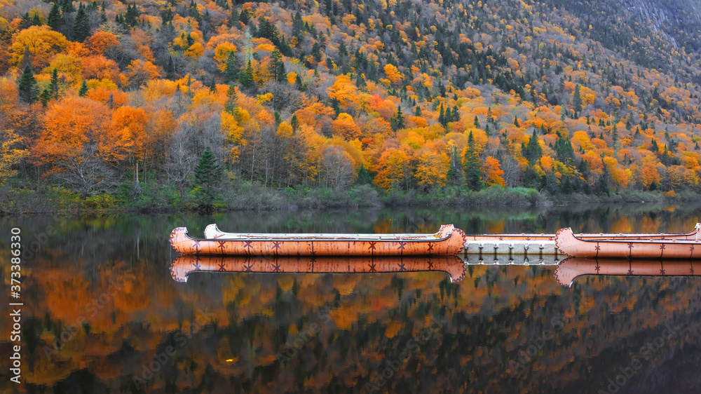 Canoes in a quite lake with fall foliage and reflections.
