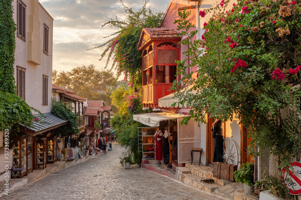 Fototapeta premium Piękna ulica na starym mieście w Kas z butikami o zachodzie słońca, Turcja