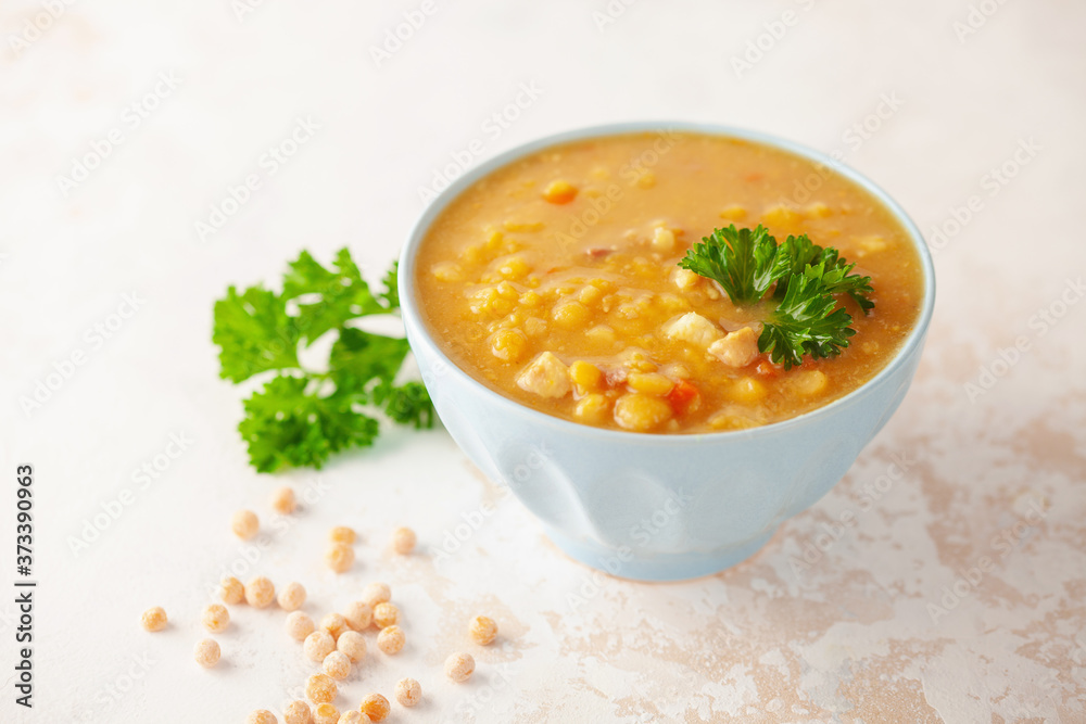 Pea soup with pieces of bacon and parsley in blue bowl on a white background. Pea soup with pieces of bacon and parsley in blue bowl on a white background.