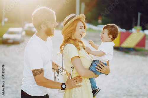 Beautiful red-haired woman with her husband and a wonderful son walking on a summer beach