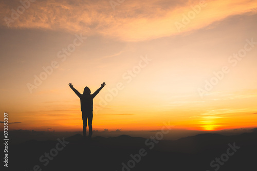 Silhouette of a woman with hands raised in the sunset concept for religion, worship, prayer and praise.