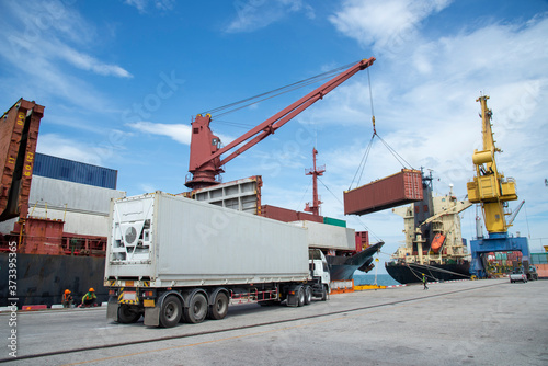 Industrial crane loading Containers in a Cargo freight ship,Container Cargo freight ship by crane bridge, logistics harbor at sunrise
