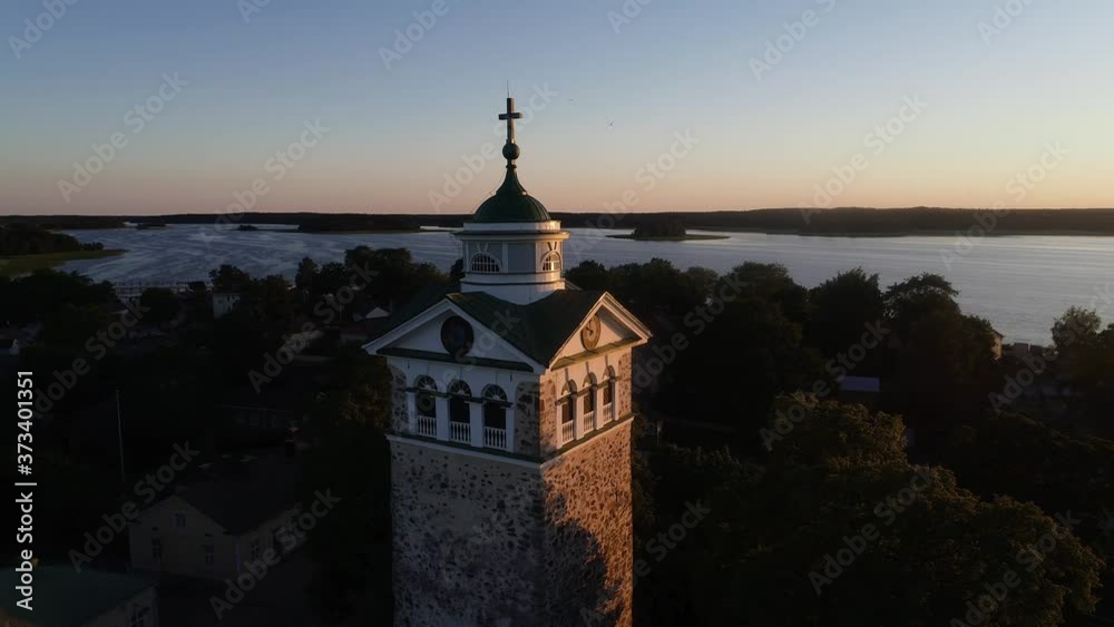 Aerial view around a church tower, in middle of the sea and houses in old town Tammisaari, on a sunny evening, in Raasepori, Uusimaa, Finland - Orbit, drone shot Aerial view around a church tower, in middle of the sea and houses in old town Tammisaari, on a sunny evening, in Raasepori, Uusimaa, Finland - Orbit, drone shot