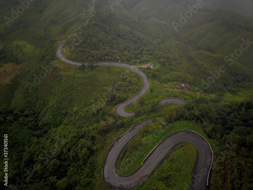 Logistic concept aerial view of countryside road - motorway passing through the serene lush greenery and foliage tropical rain forest mountain landscape