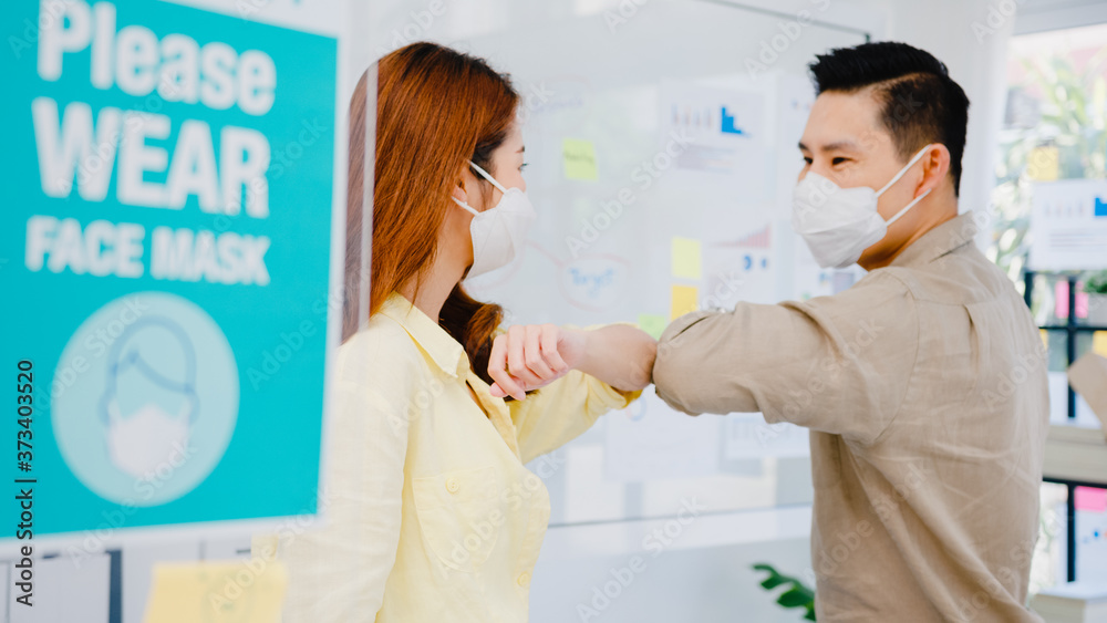 Fototapeta premium Asia businesspeople greeting with elbow bump and wear medical face mask for social distancing in new normal situation for virus prevention back at work in office. Lifestyle and work after coronavirus.