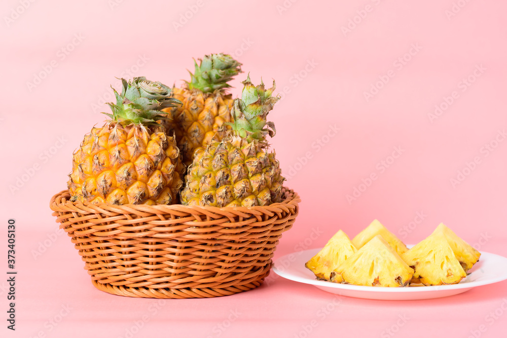 Sliced pineapple fruit on white plate and basket on pastel pink background, Tropical fruit Sliced pineapple fruit on white plate and basket on pastel pink background, Tropical fruit
